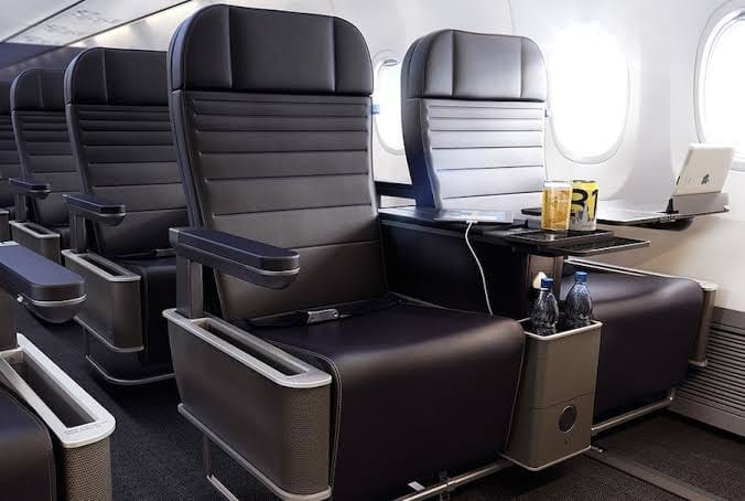 Spacious Premium Economy seats with black leather upholstery and ample legroom in an airplane cabin.